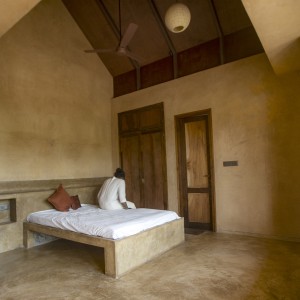 Oxide flooring and lime plaster wrap in a bedroom.