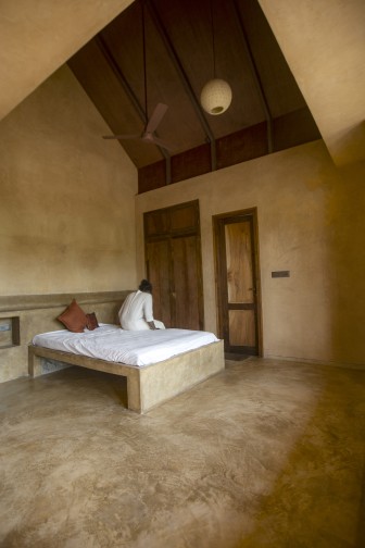 Oxide flooring and lime plaster wrap in a bedroom.